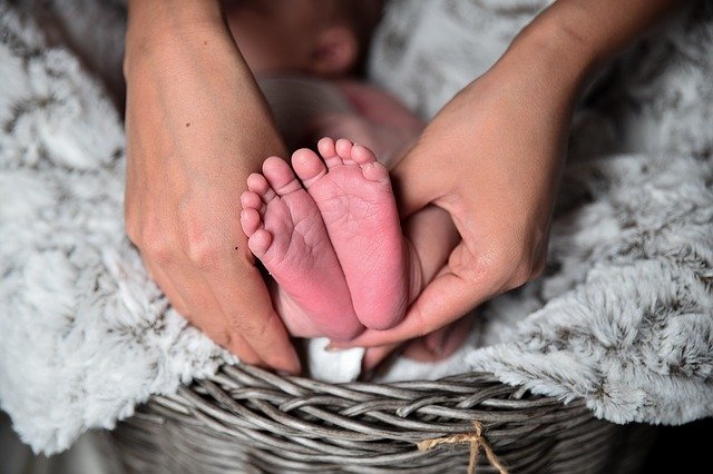 Babyfußsohlen von Mutterhänden gehalten - Leben auf breiten Füßen